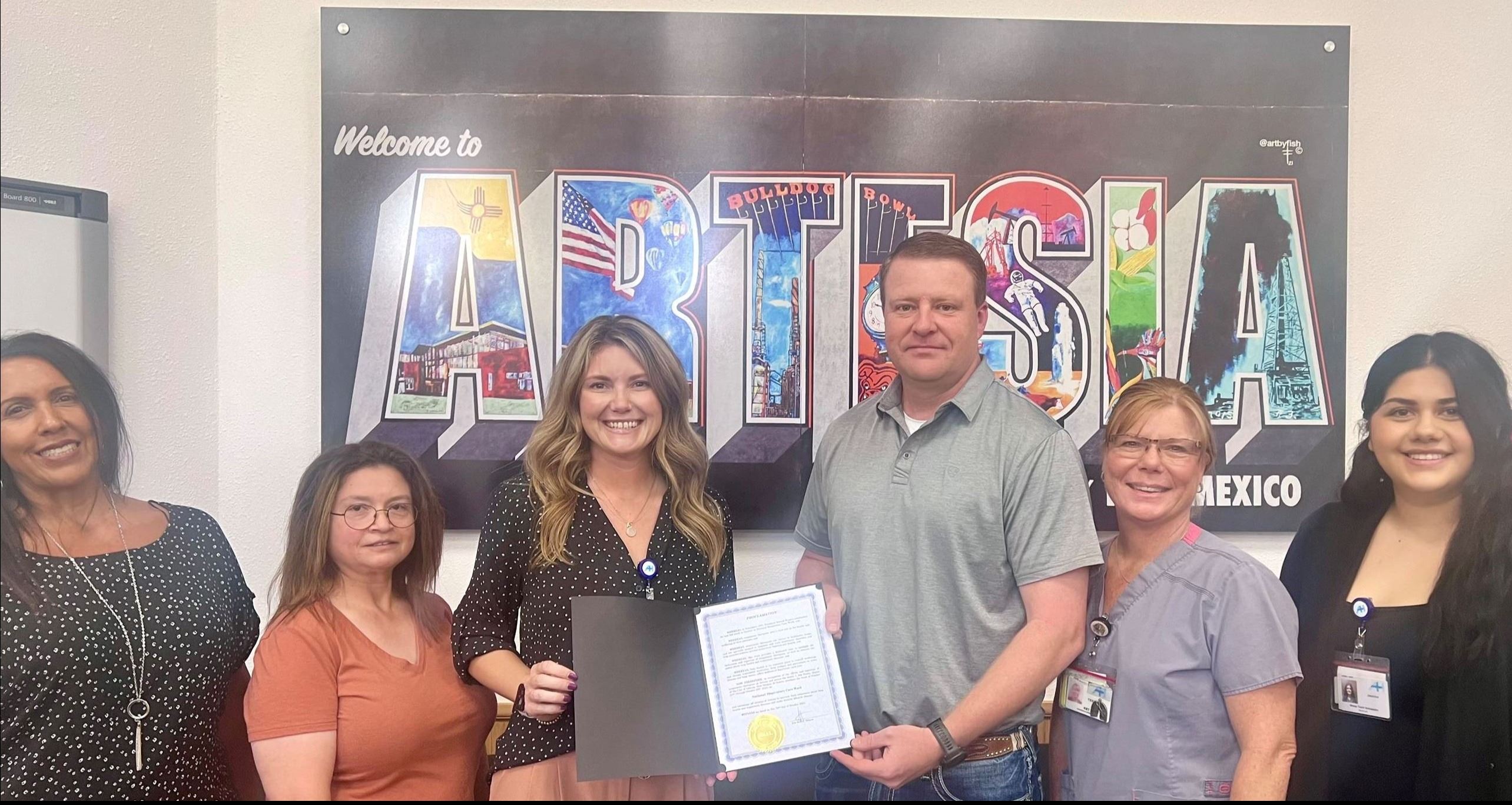 Mayor and Artesia General Hospital staff pictured in front of large Artesia art print